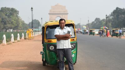 Indian auto rickshaw driver Vinod Kumar, 43, poses with his smartphone that he uses for a ride hailing app where customers can book his auto service, on a roadside near India Gate in New Delhi. AFP