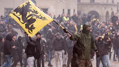 A protestor waves a Flemish flag at the police during an anti-migrant demonstration outside of EU headquarters in Brussels, Sunday, Dec. 16, 2018. AP
