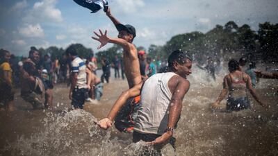 Migrants, part of a caravan from Central America en route to the US, waves the colours of the Honduran flag as they celebrate after crossing into Mexico from Guatemala through the Suchiate River. Reuters