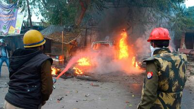 A firefighter sprays water as cars burning after being set on fire during demonstrations against India's new citizenship law in Kanpur. AFP