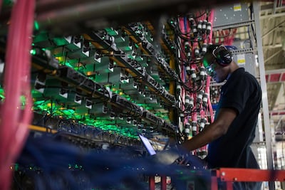 A technician monitors cryptocurrency mining rigs at a Bitfarms facility in Quebec. Bloomberg