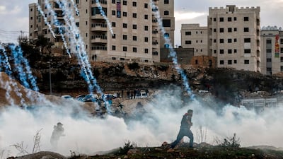Palestinian protesters run from falling tear gas canisters fired by Israeli forces during clashes near an Israeli checkpoint in the West Bank city of Ramallah as anger over the US president's controversial recognition of Jerusalem as Israel's capital continued to roil the occupied territories and the region on December 10, 2017. Abbas Momani / AFP