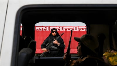 A woman with a rifle stands by an Iranian revolutionary flag during a pro-government National Army Day demonstration in Tehran. Getty Images