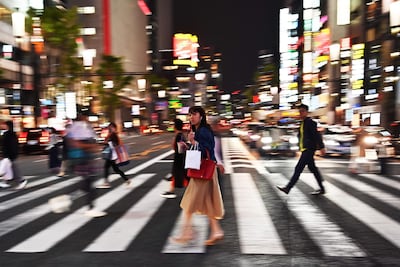 A woman crosses a street at night in Tokyo. AFP