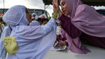 A Malaysian Muslim girl from the Little Caliphs kindergarten high-fives her teacher after completing an educational simulation of the Haj pilgrimage.