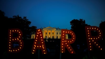 Protesters hold signs which read 'Barr', following the release of the Mueller report, at the White House in Washington. Reuters