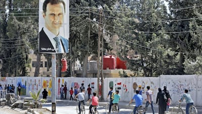 A poster of Syrian President Bashar Al Assad looks down on students going to school in the recaptured rebel-held area of Eastern Ghouta in September 2018. AFP