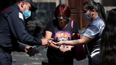 A firefighter gives disinfectant gel to women out shopping in Mexico City. AP Photo