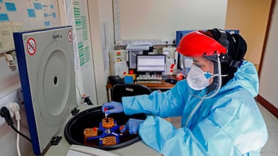 An Iranian lab technician loads a centrifuge with blood samples, taken from patients suspected of being infected with COVID-19 virus, at a hospital in Tehran. AFP