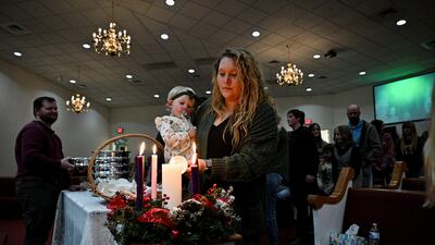 A woman holds her child as she lights a candle during a Christmas Eve service at Dawson Springs First Baptist church in, Kentucky, US. Getty