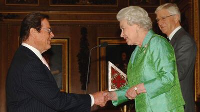Queen Elizabeth greets actor Sir Roger Moore at Windsor Castle. Getty