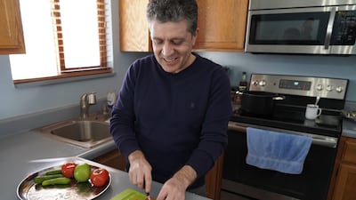 Hadi chops vegetables in his kitchen as he and his wife prepare a traditional Iraqi lunch
