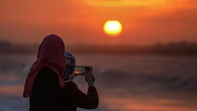 People watch the sunset at a beach in Gaza City. EPA