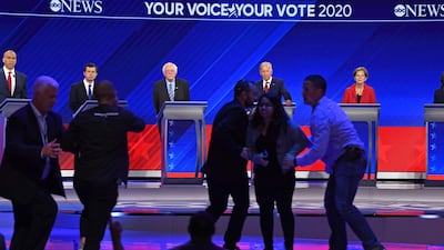 Protesters are escorted off the stage during the third Democratic primary debate in Houston, Texas. AFP