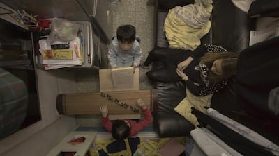 Li Suet-wen with her son and daughter in their 11-square metre room. Crammed with a bunk bed, small couch, fridge, washing machine and small table in an aging walkup in Hong Kong. She pays HK$4,500 (Dh2,200) a month in rent and utilities – nearly half her salary working in a bakery.