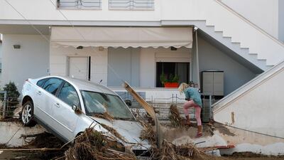 A car lies on the fence as a woman exits from the house in the village of Bourtzi, on Evia island, northeast of Athens, Greece. AP Photo
