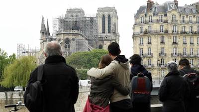People hug while looking at Notre-Dame-de-Paris on April 16, 2019 in the aftermath of a fire that devastated the cathedral. AFP