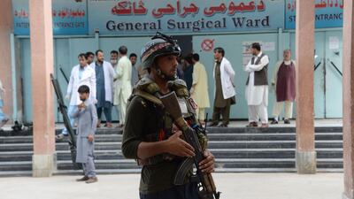An Afghan policeman stands as unseen volunteers carry an injured on a stretcher to a hospital, following an attack that targeted a parliamentary election rally in the Kama district of the eastern province of Nangarhar, in Jalalabad. AFP