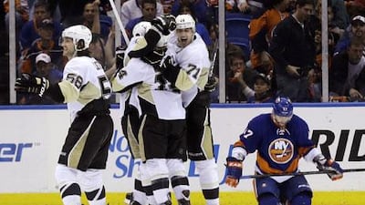 Pittsburgh Penguins' Chris Kunitz, No 14, celebrates his goal with teammates Kris Letang, No 58, and Evgeni Malkin, No 71, while New York Islanders' Andrew MacDonald, right, reacts during overtime of Game 3. Seth Wenig / AP Photo