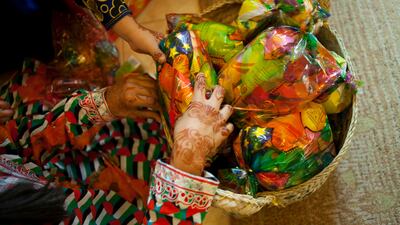 Sharjah, United Arab Emirates - June 23 2013 - Maitha Al Jabri, 4, and Hind Al-Suwaidi, 10, both cousins, pack little bags filled with sweets and crisps with at their home in the Leyyah district of the city. They are preparing for Hag El Leila, an Emirati tradition that occurs every year 15 days before the start of the month of Ramadan. The tradition involves children walking from door-to-door singing and collecting sweets and money. (Razan Alzayani / The National) FOR RYM GHAZAL STORY *** Local Caption *** RA0623_hag_el_layla_002.jpg