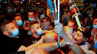 Protesters wearing protective face masks due to the Covid-19 pandemic, clash with police during a demonstration on July 18, 2020, in Charles Clore Park in Tel Aviv. AFP