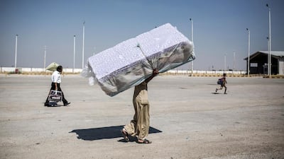 A Syrian refugee carries mattresses as he enters Syria from Turkey, after Kurdish People's Protection Units took control of the area, in Tal Abyad town, Raqqa governorate, Syria. Uygar Onder Simsek / AFP