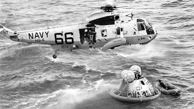 Navy UDT swimmer Clancy Hatleberg prepares to jump from a helicopter to assist the astronauts into the raft at right. US Navy / AP