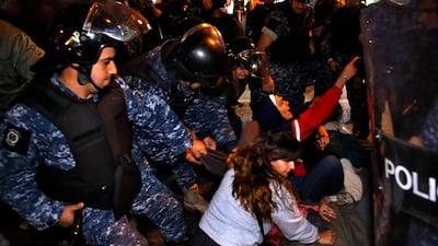 Protesters lie on a road, as they scream and hold each others while riot police try to remove them and open the road, in Beirut. AP Photo