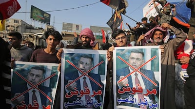 Iraqi anti-government protesters hold defaced posters of Asaad al Eidani, the governor of Basra, reading in Arabic "rejected by the people". AFP