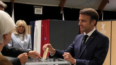 France's President Emmanuel Macron casts his ballot next to his wife Brigitte Macron during the second stage of French parliamentary elections at a polling station in Le Touquet, northern France on June 19, 2022. AFP