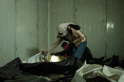 Alaa Al Qasar searches through bodies at Mujtahid hospital morgue in hope of finding her father who was arrested by the Syrian regime 12 years ago. Matt Kynaston / The National