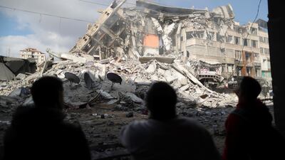 Palestinians look at the remains of a flattened tower building. Reuters
