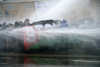 Police use water cannon on protesters as they attempt to block the transit of convoys headed to Israel in the port of Marghera, near Venice. EPA