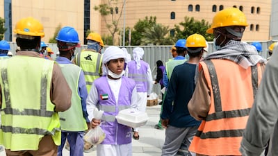A young volunteer hands out food to construction workers, part of the initiative by the Supreme Council of Motherhood and Childhood, in Abu Dhabi.