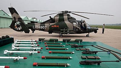 A military officer stands near a Z-9WZ attack helicopter and weapons, designed and manufactured by China during its open day to world media.