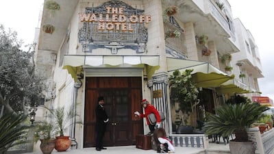 A bellboy stands outside street artist Banksy's newly opened Walled Off hotel in the Israeli occupied West Bank town of Bethlehem. Thomas Coex / AFP Photo