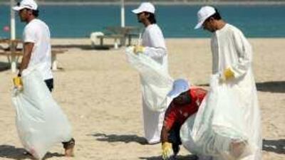 Saleh Obaid of Al Jazeera, left, and the Al Wahda player Ismail Matar, in red, helped clean up the New Corniche Beach in Abu Dhabi.