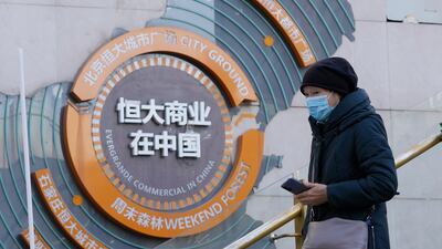 A woman passes a display showing Evergrande's commercial projects in Beijing. The company has more than $300 billion of debt and is considered the world’s most indebted developer. AP