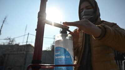 A student sanitises her hands before entering a college which reopened following nearly 11 months of closure in Srinagar. AFP
