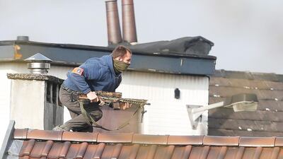 A police officer runs on top of a roof during Tuesday's antiterror operation in the Forest neighbourhood of Brussels. Laurent Dubrule/EPA