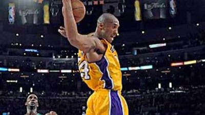 The Lakers guard Kobe Bryant dunks the ball in the second half as Celtics forward Kevin Garnett looks on.