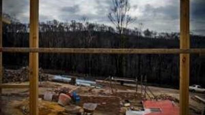 A new home under construction, front, on the outskirts of St Andrews, one of the hardest hit towns in the bushfires that raged through the southern Australian state of Victoria earlier this year. Sue Aldred, above, 53, is one town resident who has decided to rebuild rather than move away.