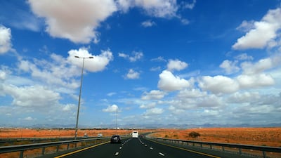 Blue skies intermingled with white clouds against the backdrop of the UAE's desert and mountains.