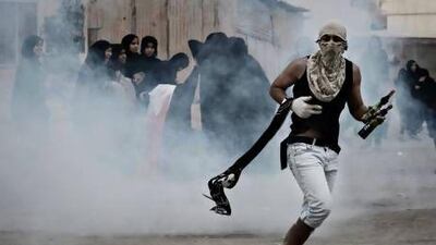 A Bahraini Shiite protester, holding petrol bombs, runs for cover from tear gas fired by riot police during clashes in the village of Samahij on November 13.