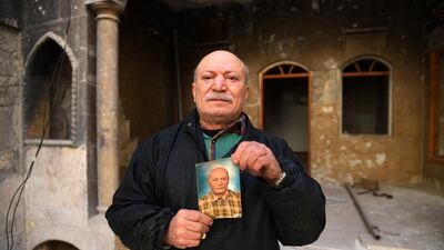 Ahmed Nashawi, also known as Abu Abdo, poses with a portrait of himself from ten prior ago outside his destroyed house in Syria's northern city of Aleppo on February 22, 2021. The man in his fifties, once one of the city's most popular fishmongers, said his home and shop on Sahat Al Hatab square were obliterated in clashes between rebels and pro-government fighters in 2015. AFP