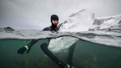 Swedish surfer Pontus Hallin waits for waves while sitting on his surfboard made of ice at the Delp surfing spot, near Straumnes, in the Lofoten Islands, over the Arctic Circle. AFP