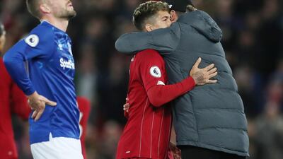 Liverpool manager Juergen Klopp celebrates with Roberto Firmino as Everton's Gylfi Sigurdsson looks dejected. Reuters