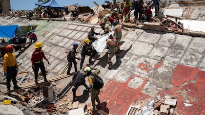 Rescue workers recover a body from the rubble of a building destroyed by earthquakes in La Guaira, Venezuela. Two earthquakes struck the country in quick succession on June 24. EPA