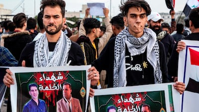 Protesters wearing bandages crossing their mouths stand holding up signs showing the faces of two slain journalists captioned in Arabic "martyrs of the word" during an anti-government demonstration, also calling for freedom of the press, in the southern Iraqi city of Basra. AFP