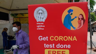 A man walks past a board from the Ahmedabad Municipal Corporation at a temporary Covid-19 testing centre in Ahmedabad. AFP